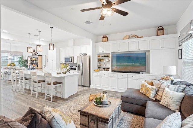 living room with sink, light hardwood / wood-style floors, and ceiling fan