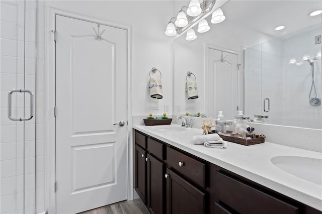 bathroom featuring hardwood / wood-style floors, a shower with door, and vanity