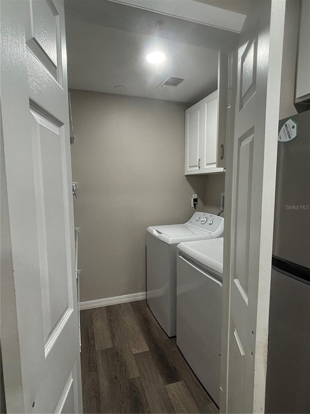 laundry area featuring washing machine and clothes dryer, dark hardwood / wood-style floors, and cabinets