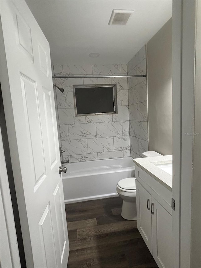 full bathroom with hardwood / wood-style floors, toilet, vanity, and tiled shower / bath