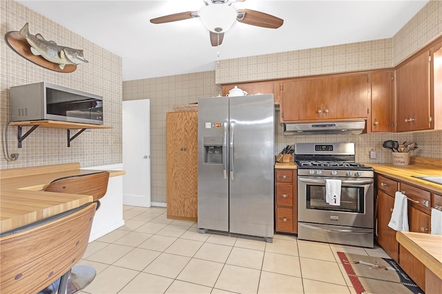 kitchen featuring ceiling fan, light tile patterned floors, backsplash, and appliances with stainless steel finishes