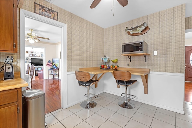 kitchen featuring ceiling fan, decorative backsplash, and light tile patterned flooring