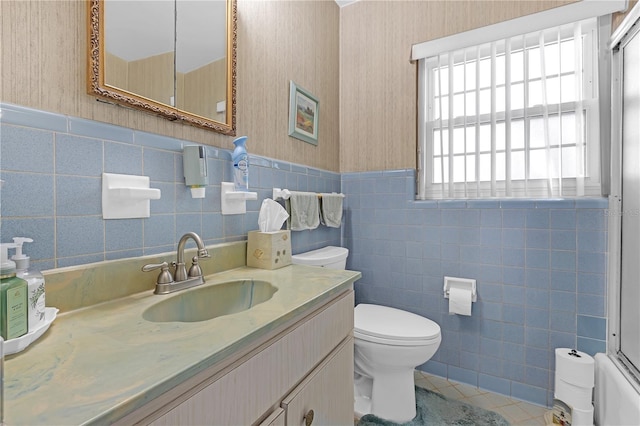 bathroom featuring toilet, vanity, tile walls, and tile patterned floors