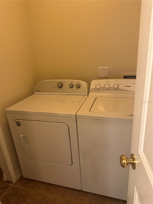 clothes washing area with dark tile patterned flooring and washing machine and clothes dryer