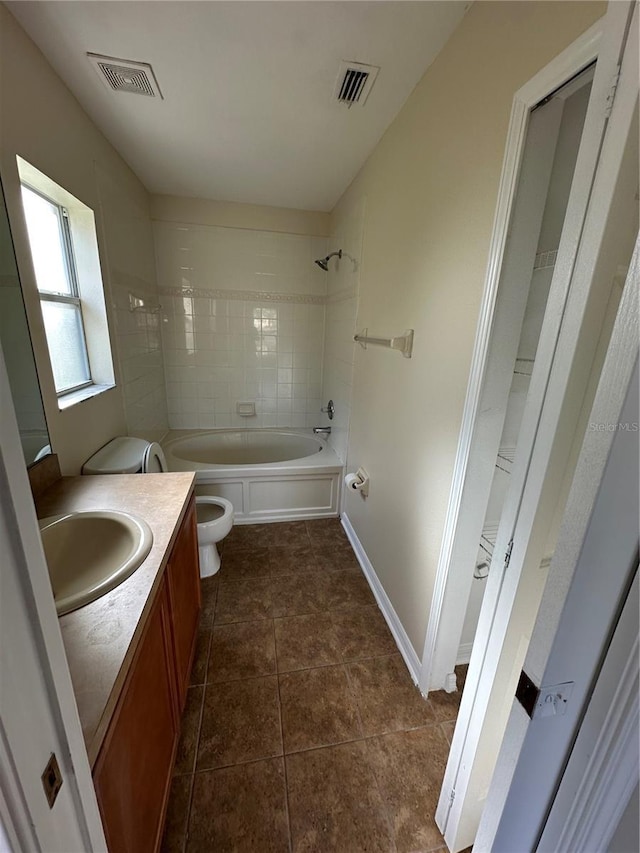 full bathroom featuring vanity, toilet, tiled shower / bath, and tile patterned flooring