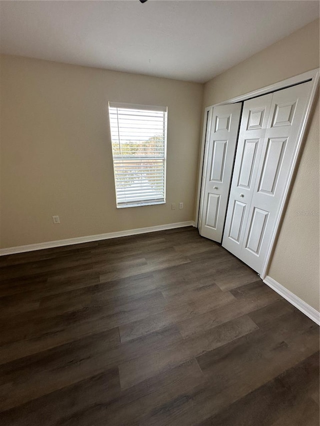 unfurnished bedroom featuring dark wood-type flooring and a closet