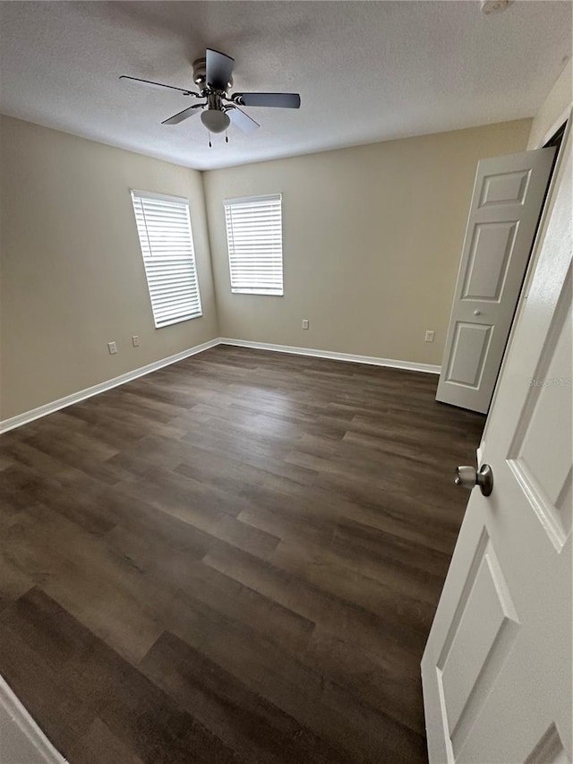 empty room with a textured ceiling, ceiling fan, and dark hardwood / wood-style flooring