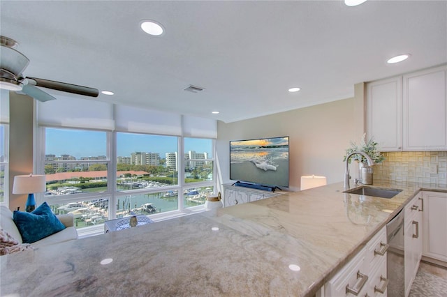 kitchen featuring sink, white cabinets, backsplash, light stone counters, and kitchen peninsula