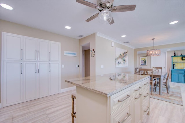 kitchen featuring ceiling fan with notable chandelier, white cabinetry, light stone counters, a kitchen island, and decorative light fixtures