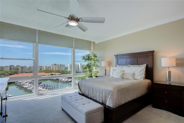 bedroom with a water view, light colored carpet, and ceiling fan