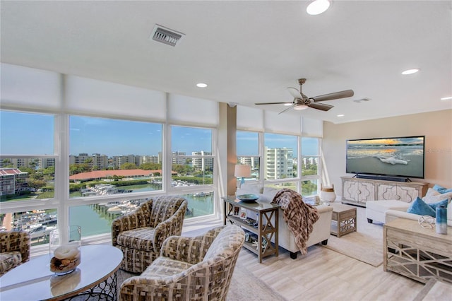 living room featuring a water view, ceiling fan, and light hardwood / wood-style floors