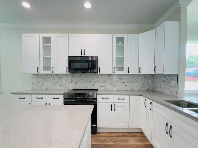 kitchen featuring hardwood / wood-style flooring, white cabinets, ornamental molding, and electric range