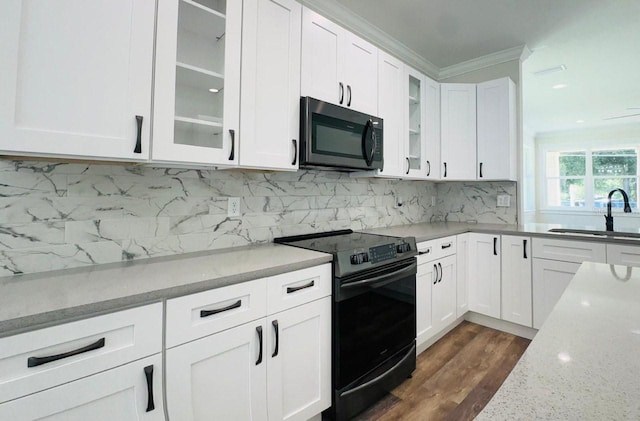 kitchen with black electric range oven, sink, white cabinets, ornamental molding, and light stone countertops