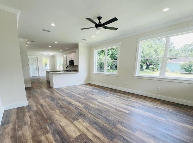 unfurnished living room featuring ceiling fan, ornamental molding, dark hardwood / wood-style floors, and sink