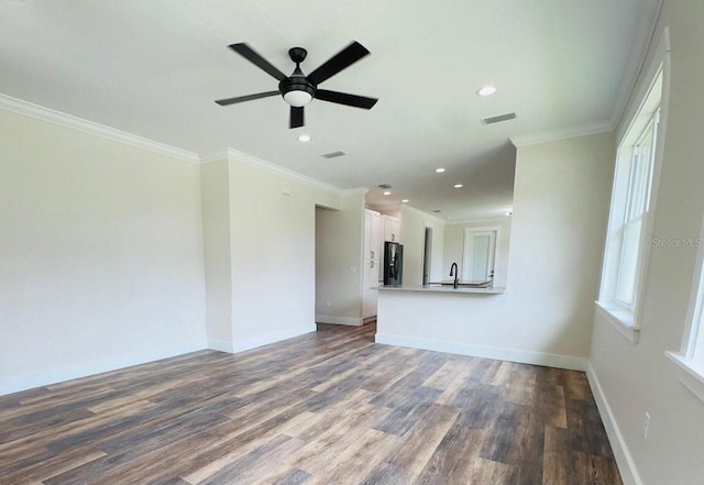 unfurnished living room with sink, crown molding, wood-type flooring, and plenty of natural light