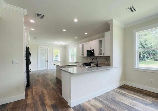 kitchen featuring sink, white cabinetry, tasteful backsplash, black appliances, and kitchen peninsula