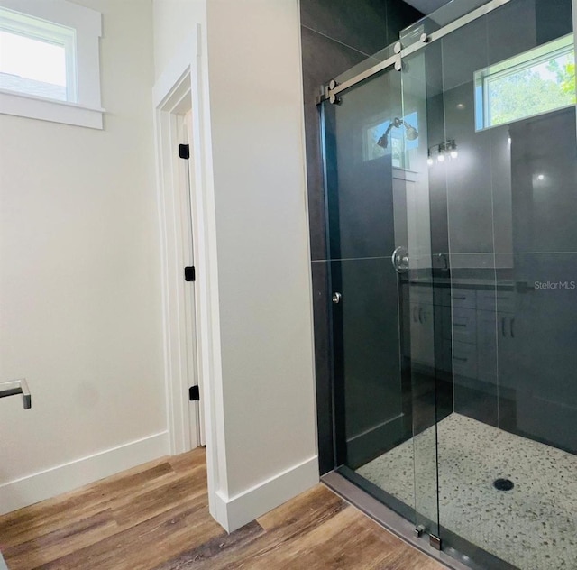 bathroom with a healthy amount of sunlight, wood-type flooring, and an enclosed shower