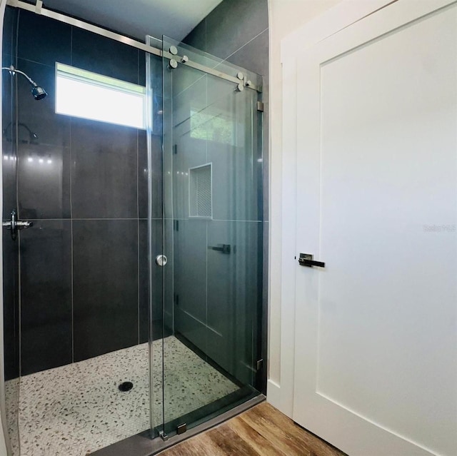 bathroom with wood-type flooring and a shower with shower door