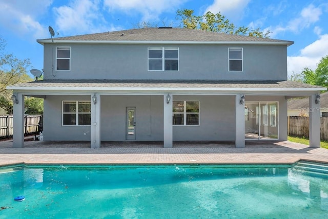 rear view of property featuring a patio and a fenced in pool