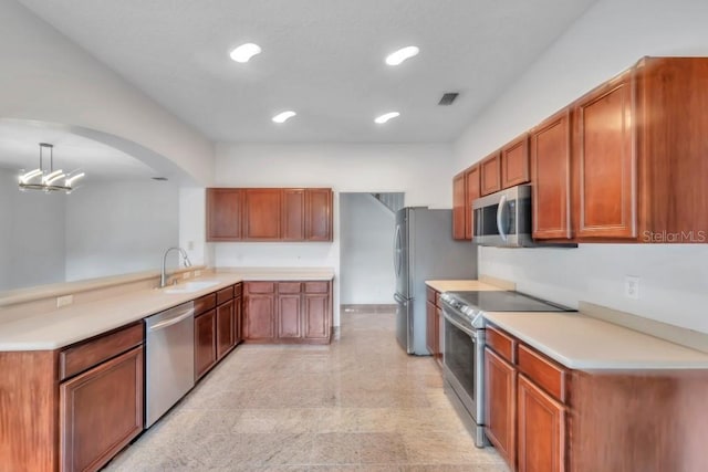 kitchen with kitchen peninsula, appliances with stainless steel finishes, decorative light fixtures, a chandelier, and sink