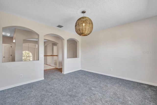 empty room with a textured ceiling and dark colored carpet