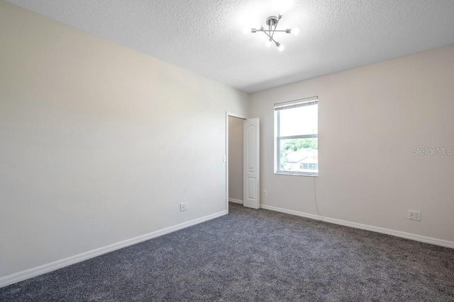 empty room featuring a textured ceiling and dark colored carpet