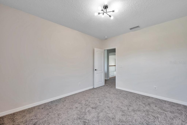 carpeted empty room featuring a textured ceiling