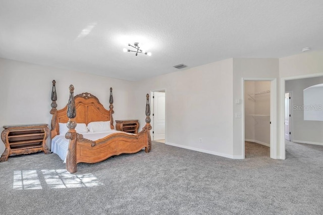 carpeted bedroom with a spacious closet, a textured ceiling, and a closet