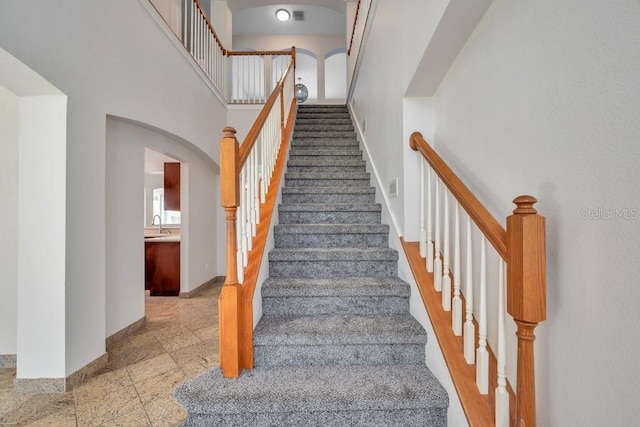 staircase with a high ceiling and sink