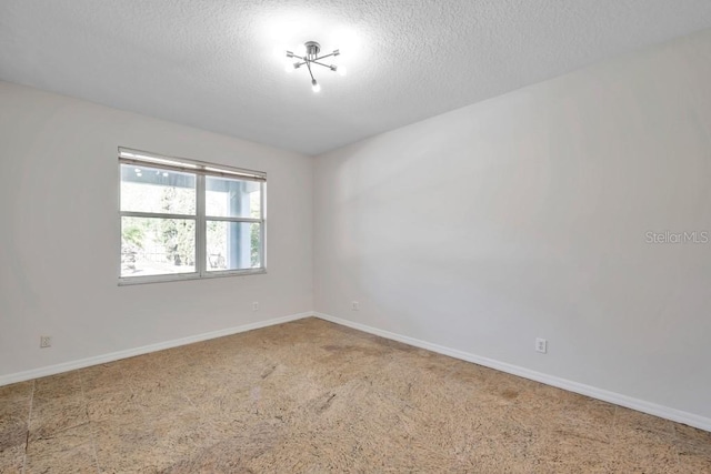 carpeted spare room featuring a textured ceiling