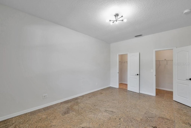 unfurnished bedroom featuring a spacious closet, a closet, and a textured ceiling