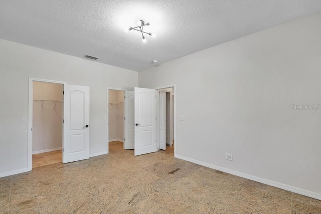 unfurnished bedroom featuring a spacious closet, a textured ceiling, and a closet