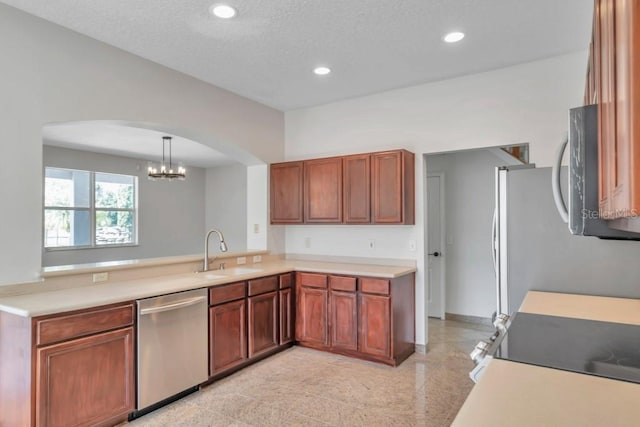 kitchen with a textured ceiling, appliances with stainless steel finishes, sink, hanging light fixtures, and kitchen peninsula