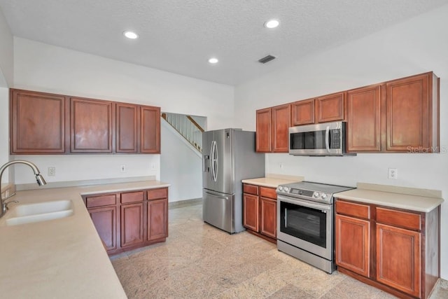 kitchen with a textured ceiling, appliances with stainless steel finishes, a towering ceiling, and sink