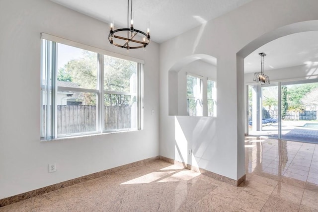 spare room with a chandelier and a healthy amount of sunlight