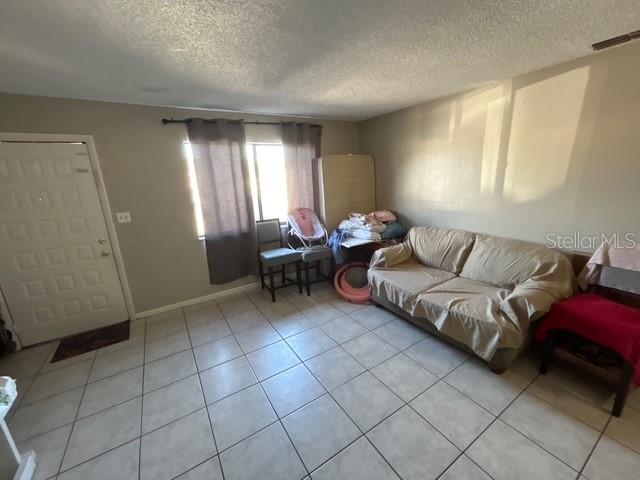 living room featuring light tile patterned flooring and a textured ceiling