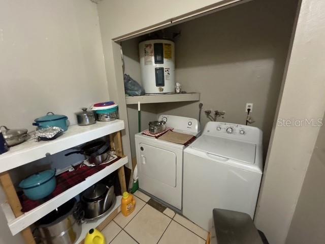 laundry room with light tile patterned flooring, washing machine and clothes dryer, and water heater