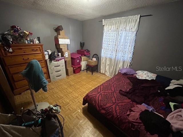 bedroom with parquet floors and a textured ceiling