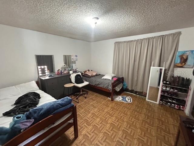 bedroom with parquet floors and a textured ceiling