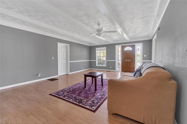 living room with hardwood / wood-style flooring, beamed ceiling, and ceiling fan