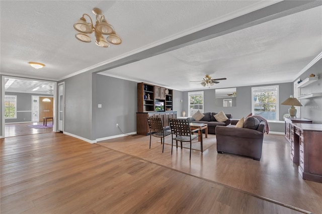 living room featuring ceiling fan with notable chandelier, hardwood / wood-style flooring, a textured ceiling, and ornamental molding