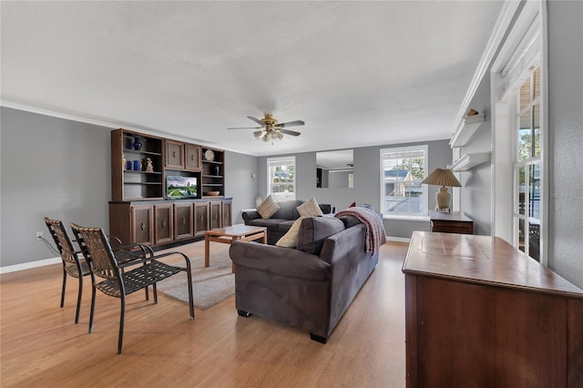 living room featuring ceiling fan, light wood-type flooring, a wealth of natural light, and crown molding