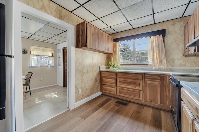 kitchen featuring light wood-type flooring, stainless steel refrigerator, a paneled ceiling, and black range with electric cooktop