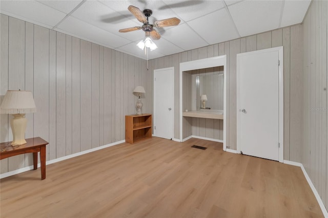 unfurnished bedroom featuring light wood-type flooring, ceiling fan, and a drop ceiling