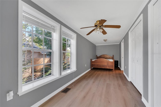 unfurnished bedroom featuring light wood-type flooring, ceiling fan, and crown molding