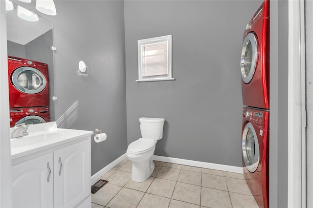 bathroom featuring vanity, stacked washer / drying machine, toilet, and tile patterned flooring