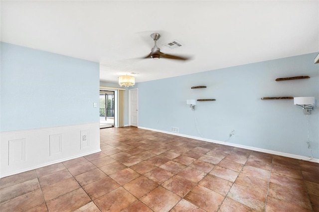 spare room featuring ceiling fan with notable chandelier