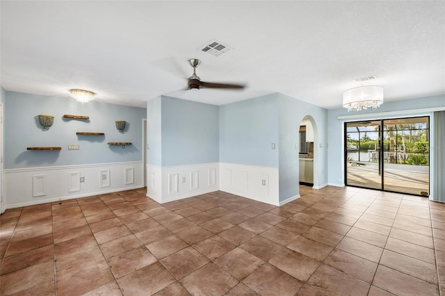 spare room featuring ceiling fan with notable chandelier and tile patterned floors