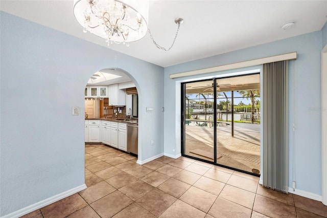 unfurnished dining area with sink, light tile patterned flooring, and a notable chandelier