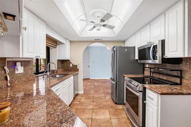 kitchen featuring sink, stainless steel appliances, white cabinetry, and dark stone counters